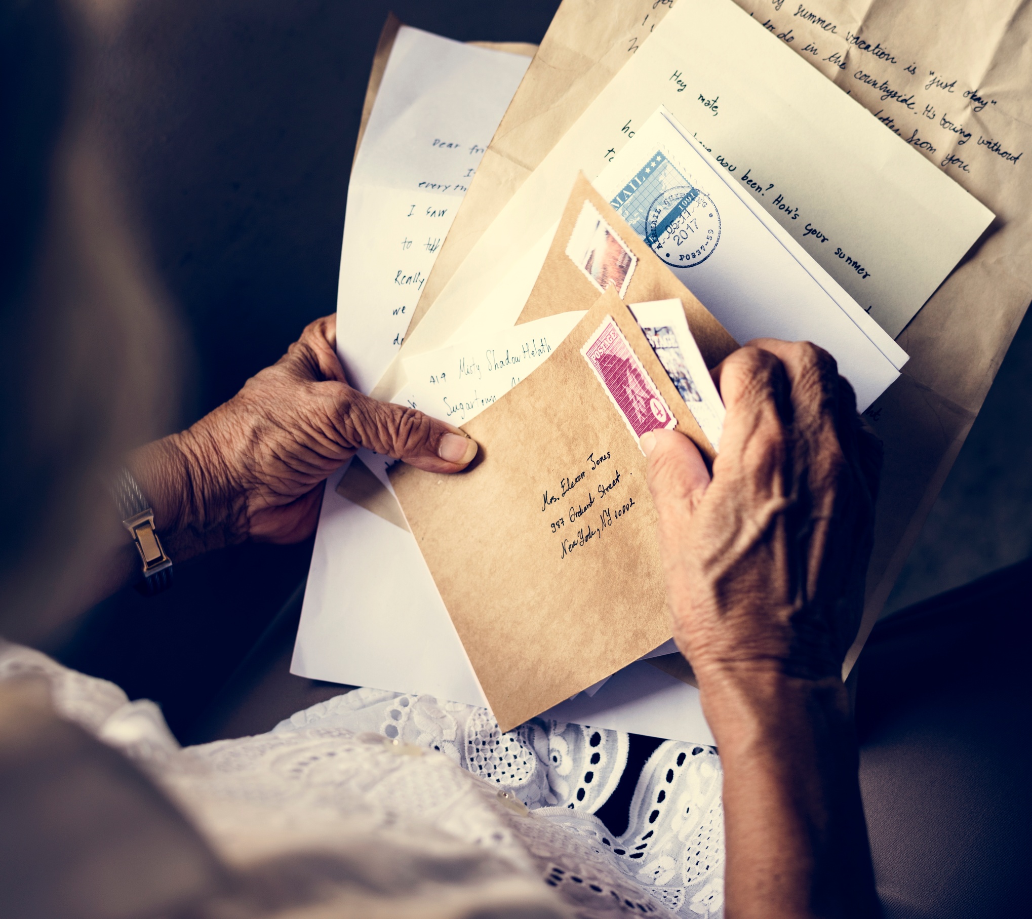 Hands holding a collection of handwritten letters and envelopes.